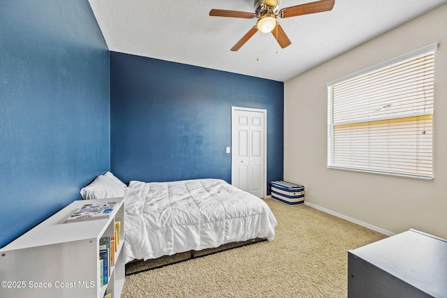 carpeted bedroom with a textured ceiling, ceiling fan, and a closet