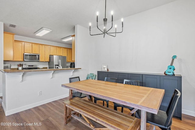 dining space featuring a textured ceiling, light hardwood / wood-style flooring, and an inviting chandelier