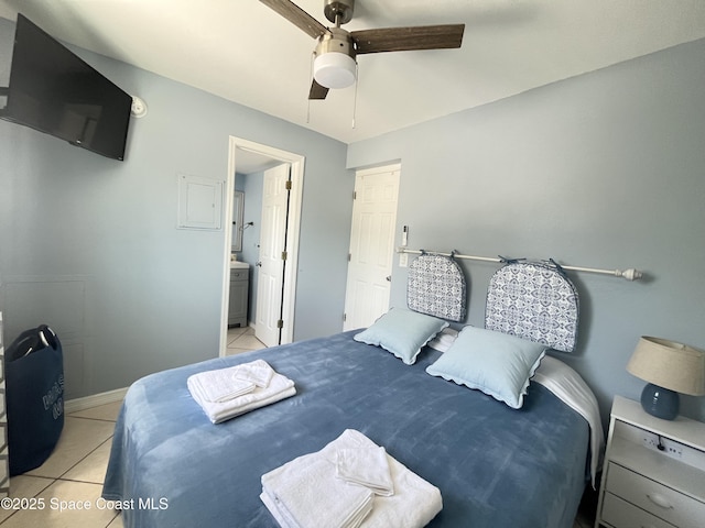 bedroom with light tile patterned floors, ensuite bath, a ceiling fan, and baseboards