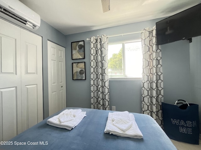 bedroom with an AC wall unit and multiple closets