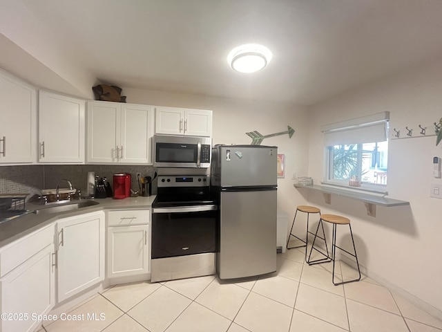 kitchen featuring white cabinets, a sink, stainless steel appliances, backsplash, and light tile patterned flooring