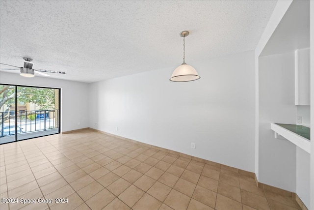 tiled spare room with a textured ceiling and ceiling fan