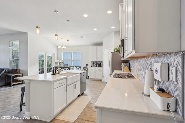 kitchen with pendant lighting, a center island with sink, white cabinets, sink, and tasteful backsplash