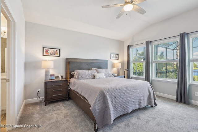 bedroom featuring light carpet, connected bathroom, vaulted ceiling, and ceiling fan