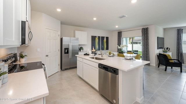 kitchen with sink, white cabinetry, light tile patterned floors, appliances with stainless steel finishes, and an island with sink