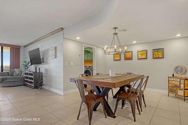 tiled dining area with a notable chandelier and washer / dryer