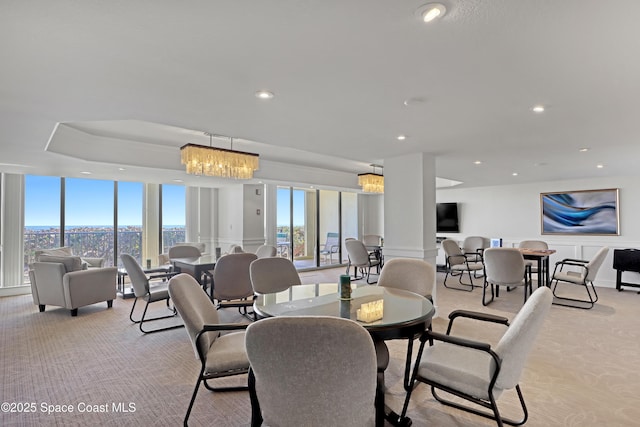 carpeted dining room with expansive windows and a notable chandelier