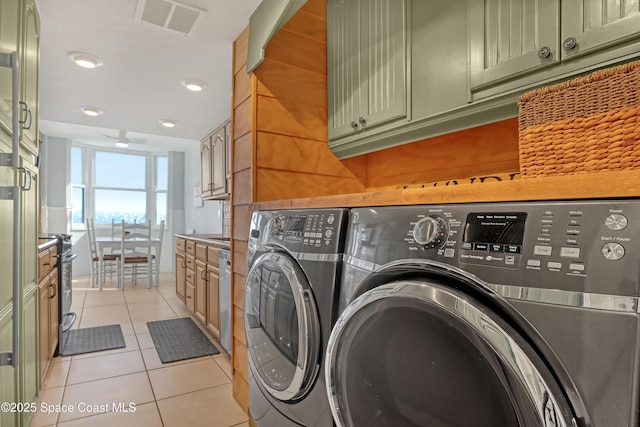 laundry room with cabinets, washing machine and dryer, and light tile patterned floors