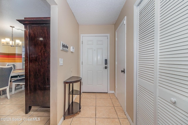 hallway featuring a textured ceiling, light tile patterned floors, and a notable chandelier