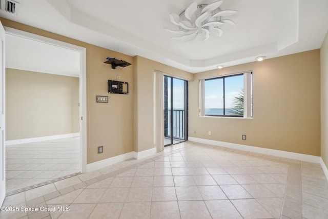 tiled empty room featuring a raised ceiling