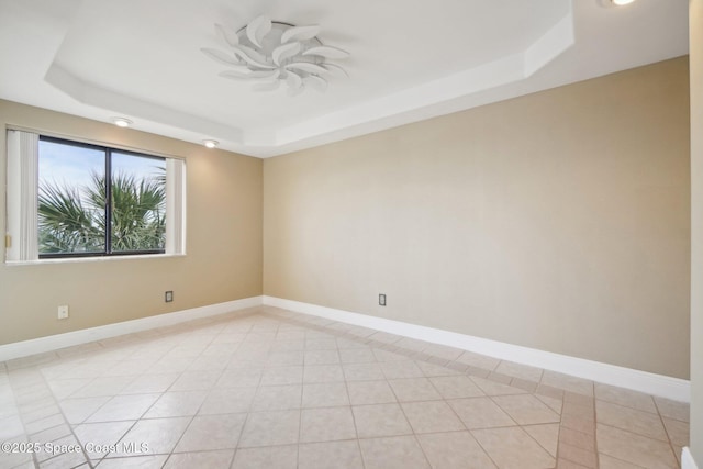 spare room featuring a raised ceiling and light tile patterned floors