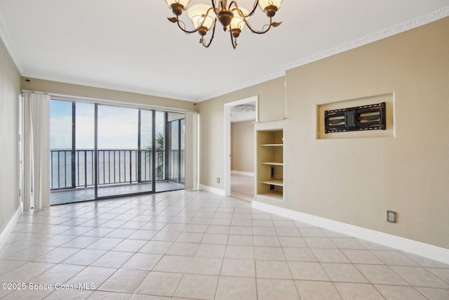 tiled spare room with built in shelves, a water view, an inviting chandelier, and ornamental molding