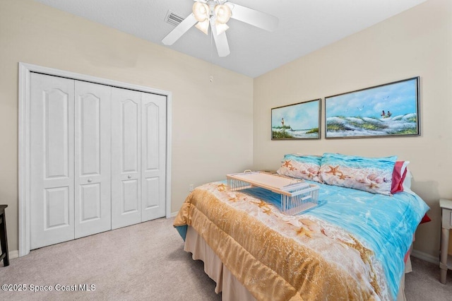 bedroom with ceiling fan, light carpet, and a closet