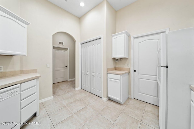 kitchen featuring light tile patterned floors, white cabinets, and white appliances