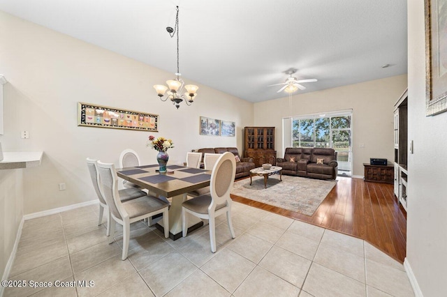 tiled dining room with ceiling fan with notable chandelier