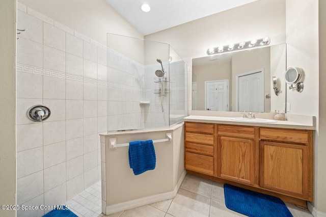 bathroom with tiled shower, vanity, tile patterned floors, and lofted ceiling