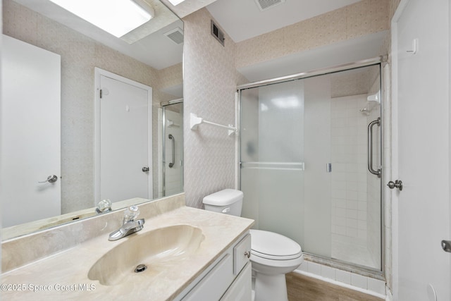 bathroom featuring a shower with shower door, hardwood / wood-style flooring, toilet, and vanity