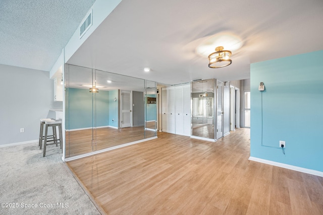 unfurnished living room with wood-type flooring and a textured ceiling