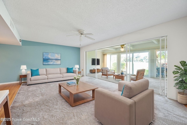 living room with ceiling fan and a textured ceiling