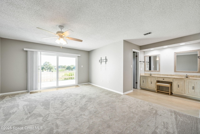 unfurnished bedroom with access to outside, light colored carpet, ensuite bath, and ceiling fan