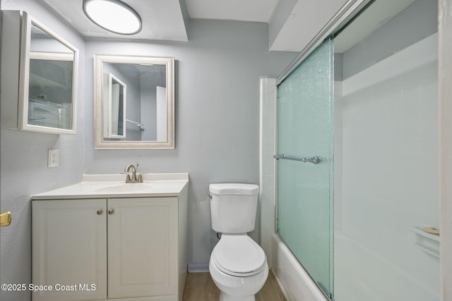 full bathroom with bath / shower combo with glass door, toilet, and vanity