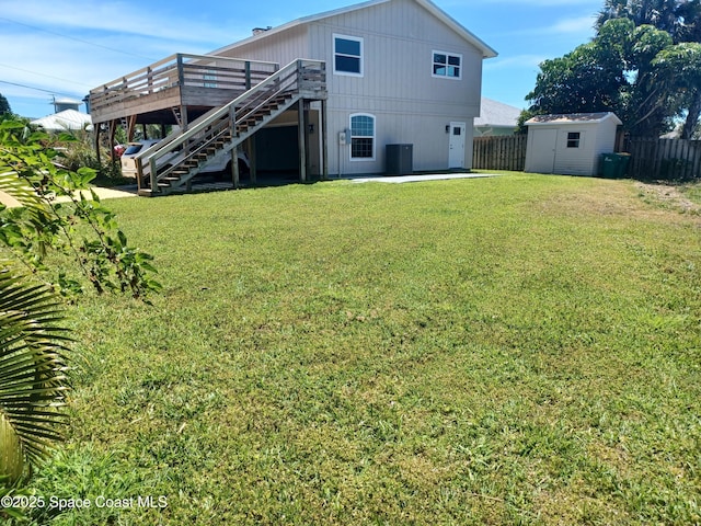 back of house featuring a lawn, a storage unit, cooling unit, and a deck