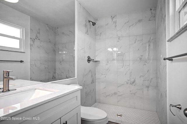 bathroom featuring toilet, vanity, and tiled shower