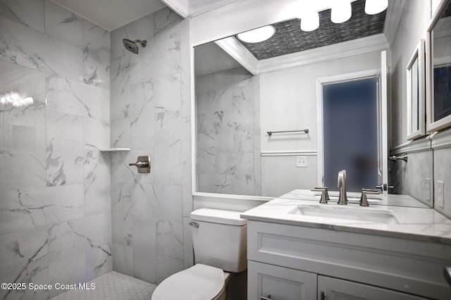 bathroom featuring vanity, toilet, crown molding, and a tile shower