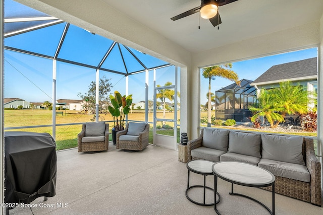 view of patio featuring grilling area, ceiling fan, outdoor lounge area, and glass enclosure