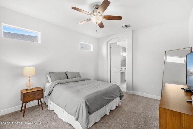 bedroom with ensuite bath, ceiling fan, and light colored carpet