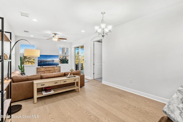 living room with ceiling fan with notable chandelier and light wood-type flooring