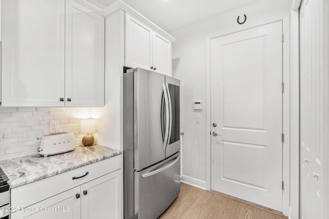 kitchen with white cabinets, stainless steel fridge, and backsplash