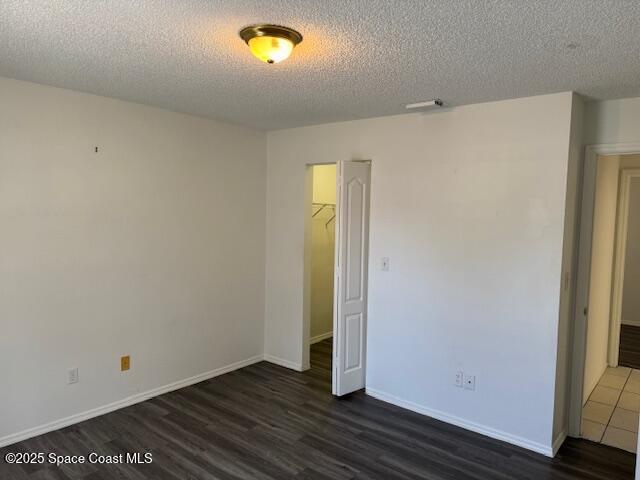 unfurnished room with dark hardwood / wood-style floors and a textured ceiling