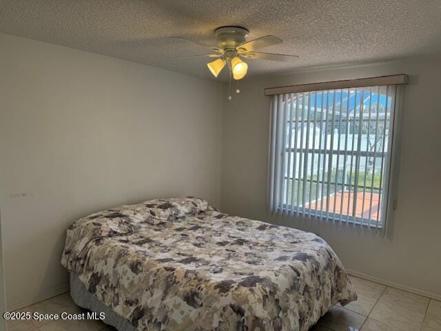 bedroom with multiple windows, a textured ceiling, ceiling fan, and light tile patterned flooring