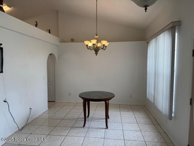 unfurnished dining area featuring light tile patterned flooring, lofted ceiling, and a notable chandelier