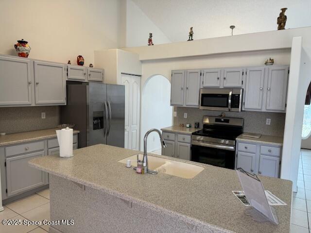 kitchen featuring light tile patterned flooring, sink, appliances with stainless steel finishes, gray cabinets, and decorative backsplash