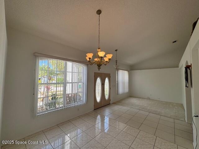 entryway with light tile patterned flooring, a healthy amount of sunlight, a textured ceiling, and a notable chandelier