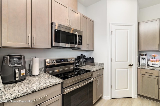 kitchen featuring light hardwood / wood-style floors, light stone countertops, and stainless steel appliances