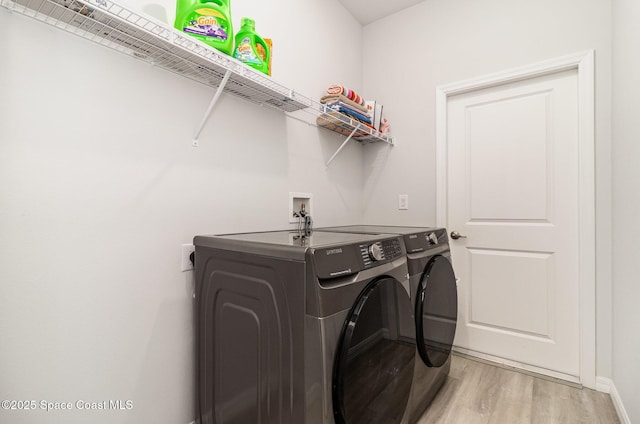 laundry area with separate washer and dryer and light hardwood / wood-style floors