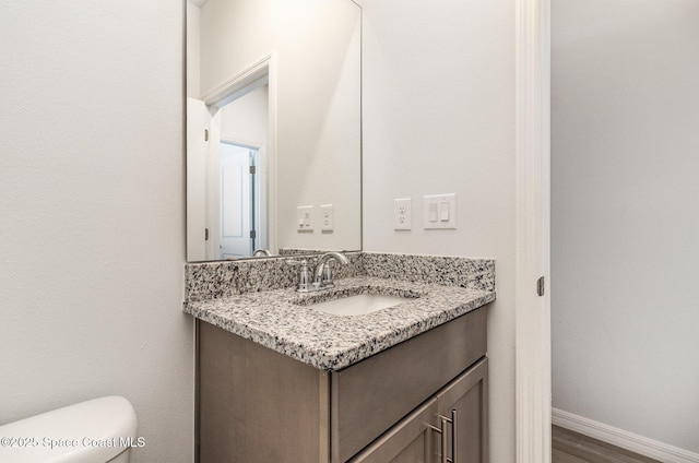 bathroom with vanity, wood-type flooring, and toilet