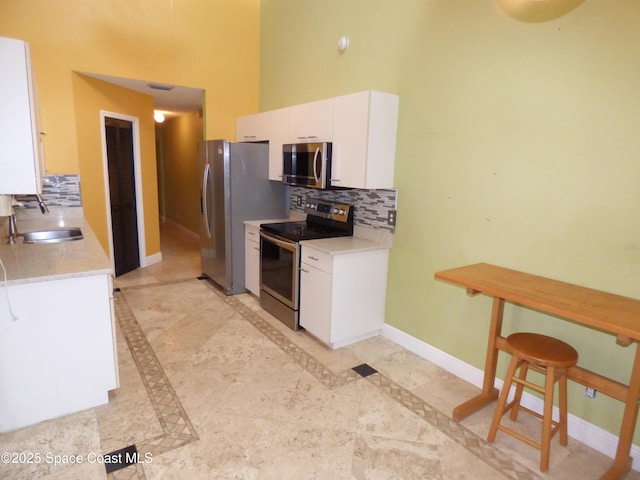 kitchen featuring white cabinets, sink, stainless steel appliances, and tasteful backsplash