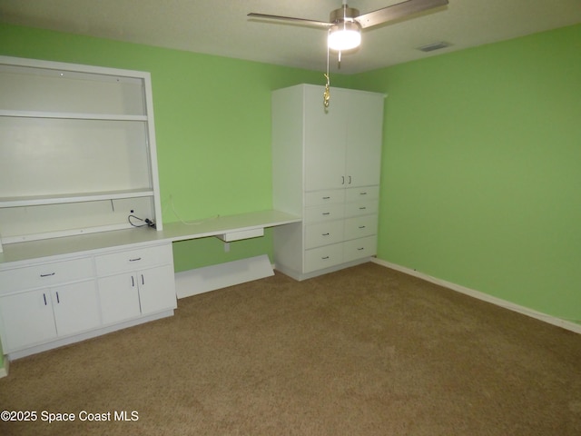 unfurnished bedroom with ceiling fan, light colored carpet, and built in desk