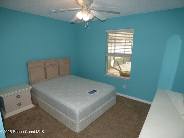 bedroom with ceiling fan, dark carpet, and a textured ceiling