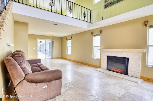 living room with ceiling fan, a fireplace, and a high ceiling