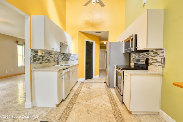 kitchen featuring white cabinets, sink, ceiling fan, appliances with stainless steel finishes, and tasteful backsplash