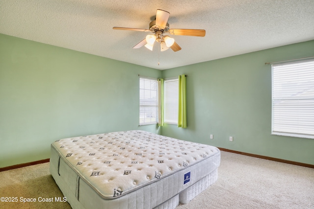 carpeted bedroom featuring multiple windows, a textured ceiling, and ceiling fan