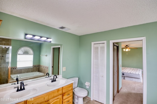 full bathroom featuring vanity, ceiling fan, separate shower and tub, toilet, and a textured ceiling