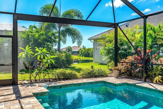 view of pool featuring a patio area, glass enclosure, and a water view