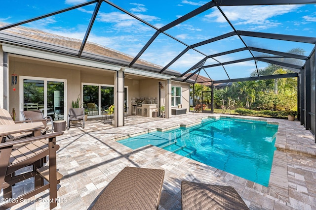 view of pool with an outdoor kitchen, a lanai, and a patio