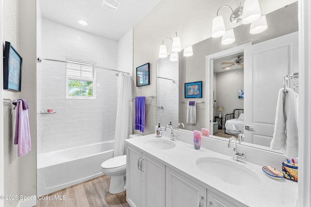 full bathroom with toilet, wood-type flooring, vanity, shower / bath combo with shower curtain, and ceiling fan